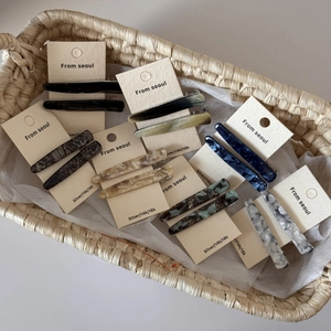 Détail de barrettes à motif marbré en acétate présentées dans un panier en paille