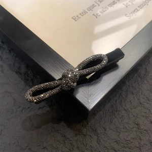 Dettaglio di un fermaglio per capelli a fiocco in velluto con strass grigio scuro