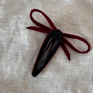 Detail showing the black metal snap clip attachment on back of a red velvet bow hair clip