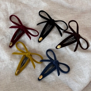Five velvet bow hair clips for girls in vintage colors with small gold metal smile tag