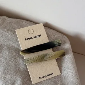 Détail de barrettes à cheveux en acétate avec motifs d'écailles sur carte en papier