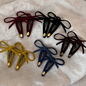 Detail view of colorful velvet bow hair clips with gold smile engraved metal tags