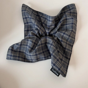 Detail of grey plaid fabric scrunchie with classic checkered pattern and brand woven label