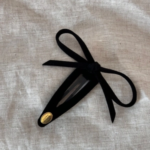 Detailed view of the black velvet bow hair clip with an engraved gold metal plate