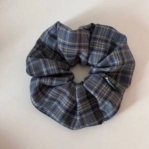 Detail view of navy blue plaid fabric scrunchie with classic checkered textile pattern