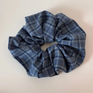 Close-up of classic navy blue plaid scrunchie with soft pleated fabric and elastic core