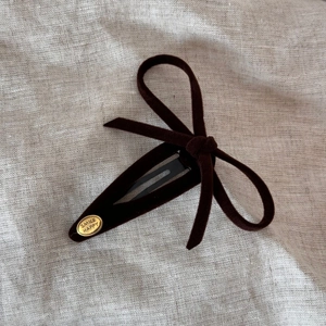 Detail of vintage velvet bow hair clip with a gold SMILE HAPPY metal charm on fabric