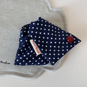 Detail eines marineblauen Stoff-Accessoires mit roten Punkten und Hand Made Etikett