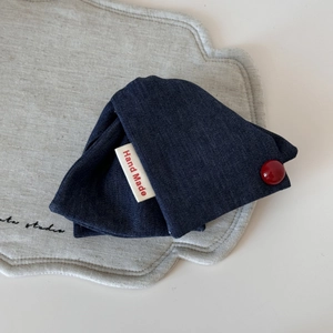 Detail einer Haarklammer aus Denim mit Hand Made Etikett und rotem Knopfdekor