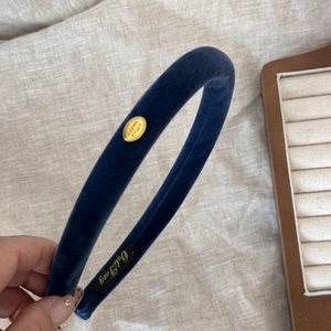 Close-up of navy blue velvet padded headband with a golden Smile Happy metal tag
