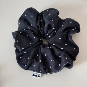 Detail view of denim scrunchie with white heart pattern and AWESOME.US fabric label