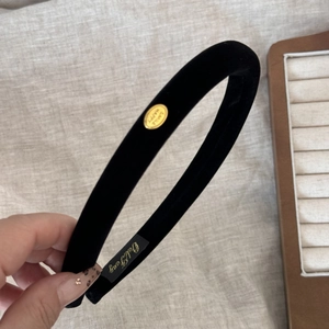 Detailed macro view of black velvet headband with a gold SMILE HAPPY oval metal buckle