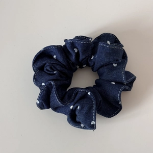 Close-up of dark blue denim hair scrunchie with white heart pattern and contrast stitching