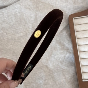 Close-up of dark brown velvet headband featuring golden metal plate with Smile Happy text