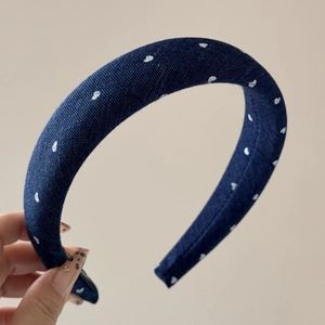 Detail of navy blue denim headband featuring white heart patterns and premium stitching