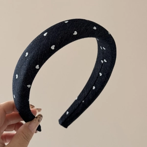 Close-up of black denim headband with white heart patterns showing thick padded design