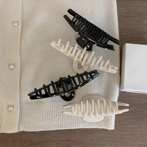 Detailed view of rectangle rhinestone hair claw clips in black and cream on knit fabric