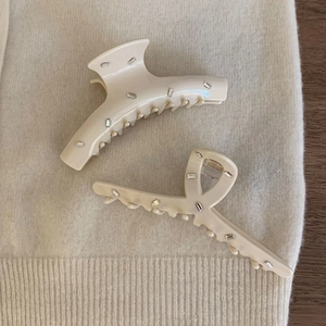 Beige acetate hair claw clips set with rectangular rhinestones on knit background