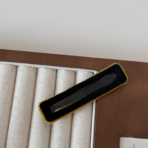 Detail of a rectangular velvet hair clip with contrast black and yellow flocking