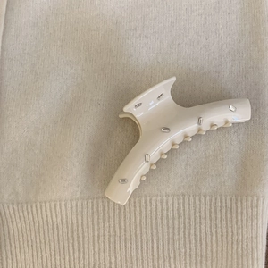 Detail of a cream acetate hair claw clip with rectangular rhinestones on knitted fabric