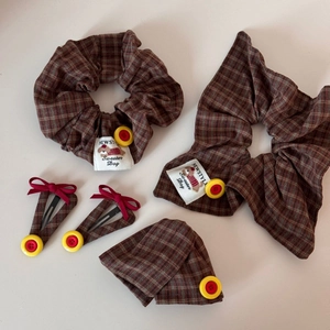 Detailed view of brown plaid scrunchies with red heart buttons and cute dog woven labels