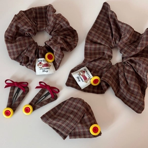 Detail view of brown plaid scrunchies and BB clips with yellow buttons and dog labels