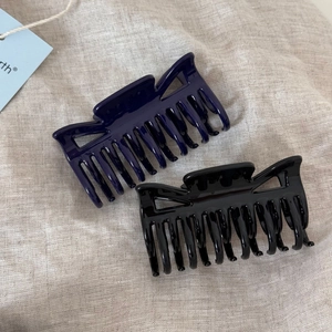 Detail of glossy navy blue and black hair claws on light grey linen fabric