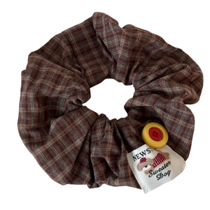 Brown plaid scrunchie with yellow button detail and cartoon sweater dog label