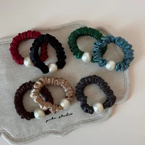 Detail of satin scrunchies with elegant pearls in various Morandi colors and silk texture