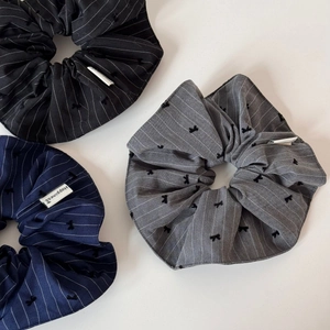 Detail view of striped hair scrunchies with black bow embroidery and fabric labels