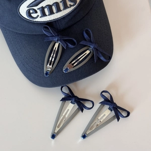 Detail of four denim blue ribbon hair clips with rhinestones on a cap background