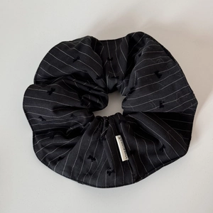 Detail showing black striped scrunchie with embroidered bows and Happiness label