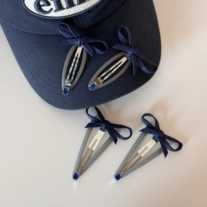 Detail of four navy blue bow hair clips with blue rhinestones on a baseball cap brim