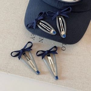 Blue denim bow hair clips set with rhinestones on a baseball cap and fabric backdrop