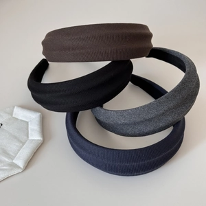 Detail of four knitted headbands in brown, black, grey, and navy with ribbed texture