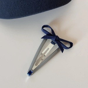 Detailed view of denim bow hair clip with blue rhinestone and dark grey matte clip base