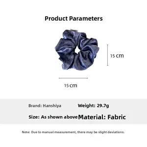 Detail view of a blue velvet hair scrunchie with gold polka dots showing its 15cm size