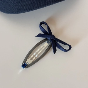 Detail of denim bow snap clip with blue rhinestone and translucent resin frame