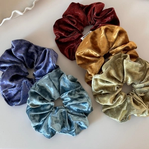 Detailed close-up of colorful velvet scrunchies with white brand labels and polka dots