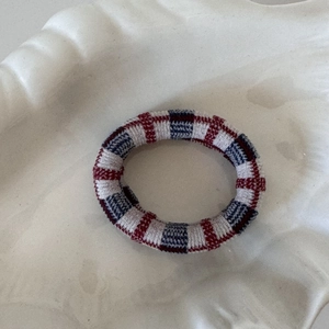 Détail de l'élastique à cheveux à carreaux rouge et bleu sur un plateau blanc