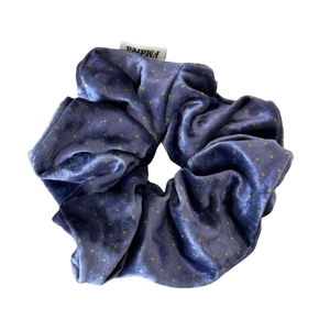Violet blue velvet scrunchie with yellow polka dots and brand label on white background