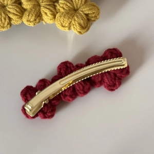 Detail view of handmade wine red crochet flower hair clip on a golden metal base