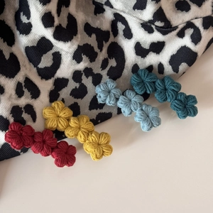 Set of four handmade crochet flower hair clips in red, yellow, blue, and teal colors