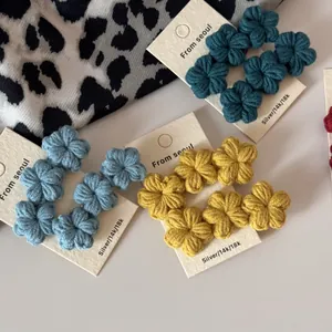 Close-up of handmade crochet flower earrings in blue and yellow on jewelry cards