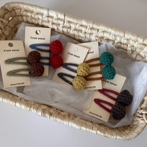 Handmade colorful crochet hair clips with pom-poms for girls in a woven basket