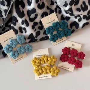 Close-up of handmade crochet flower hair clips in vintage green, blue, yellow, and red colors