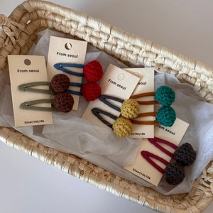 Detail of handmade colorful crochet ball hair clips in a woven basket display
