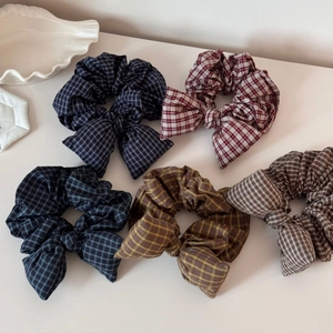 Flat lay of five plaid bow hair scrunchies in navy, red, blue, yellow, and brown tones