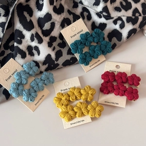 Detailed macro view of handmade crochet flower earrings in peacock blue and red gradient