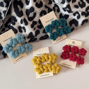 Detailed macro view of 3D crocheted flower hair clips in four vibrant gradient colors